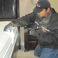 Bed bug inspection technician checking a mattress and bed frame for signs of infestation in Sioux Falls, SD