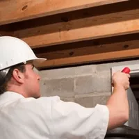Termite inspection technician checking a basement wall and framing for termite activity in Sioux Falls, SD